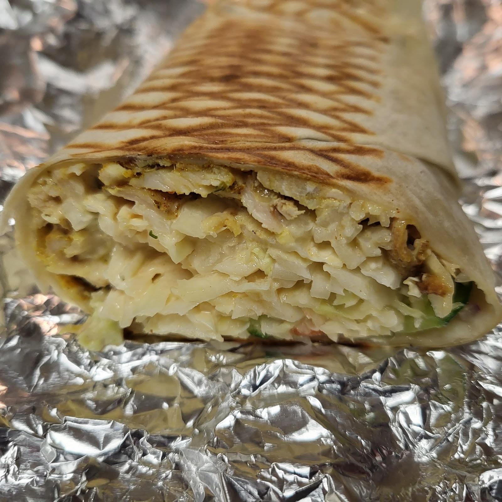 Kebab w folii aluminiowej z bliska, świeże mięso z noża