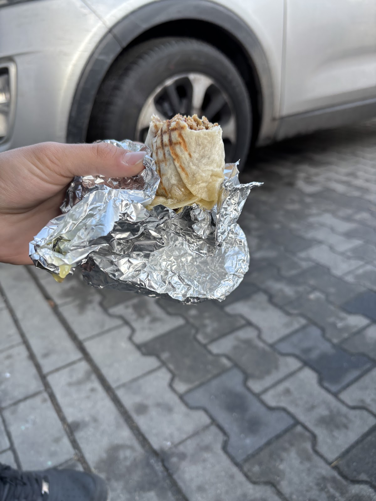 Kebab w foli w dłoni, opakowanie do wzięcia ze sobą